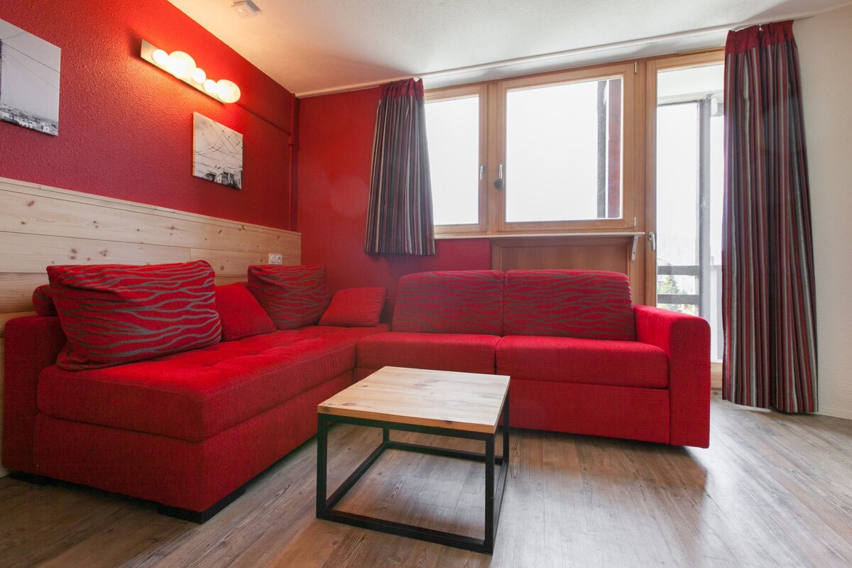 A living room with a red couch and a wooden table