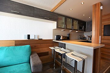 A living room with a blue couch and a kitchen