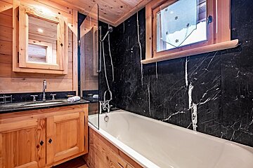 A bathroom with black marble walls and a bathtub