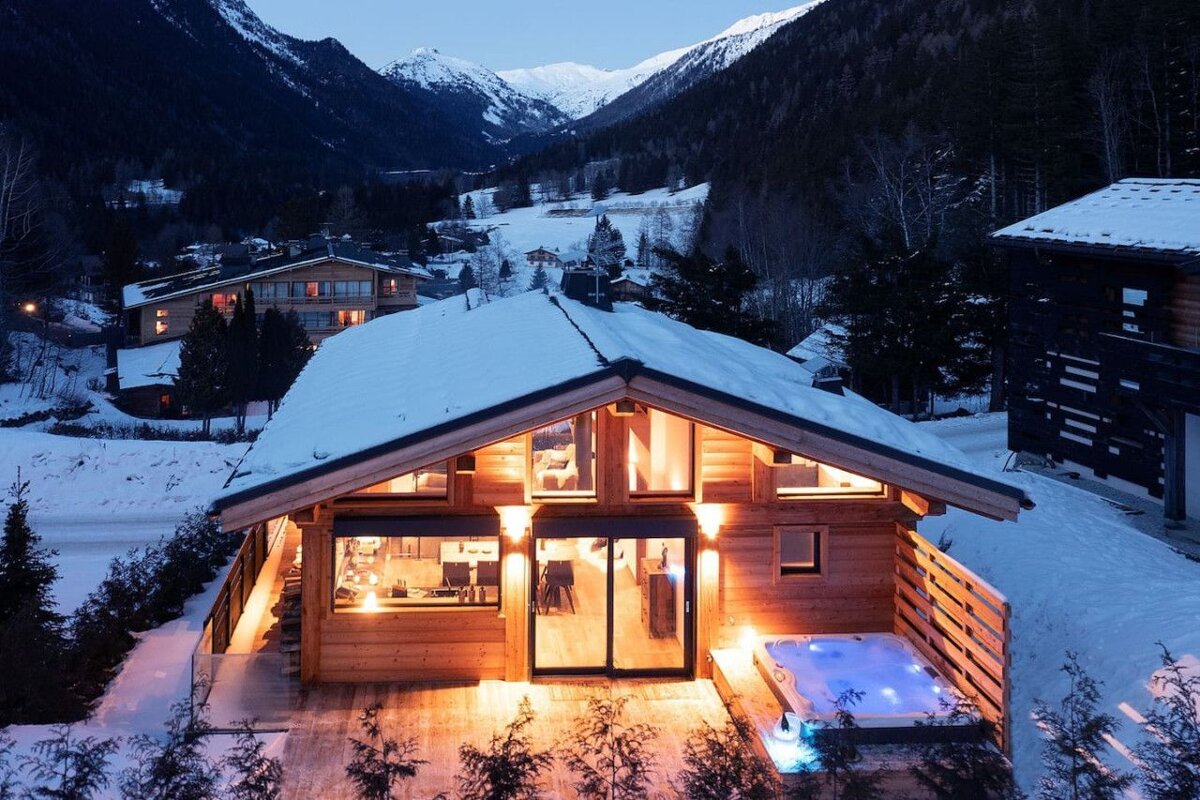 A snowy house with a hot tub in front of it