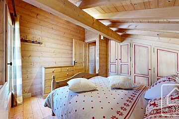 A bedroom in a log cabin with a bed and dresser