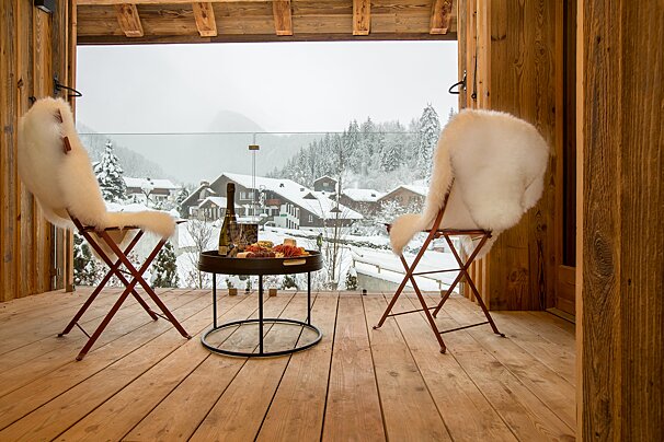 Two chairs and a table with a bottle of wine on it
