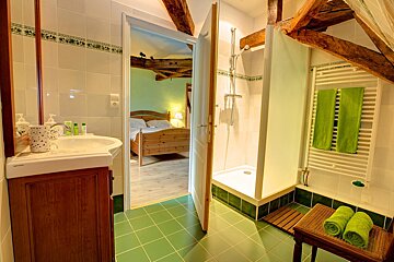 A bathroom with green tiles and a white towel rack