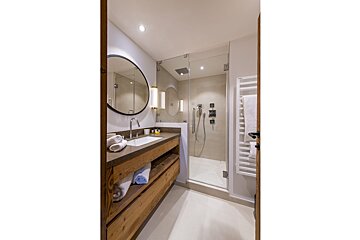 A bathroom with a sink a mirror and a walk in shower