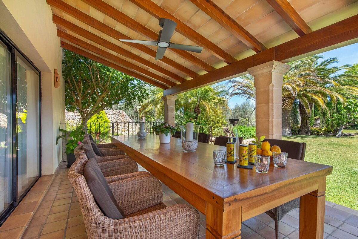 A long wooden table with wicker chairs under a ceiling fan