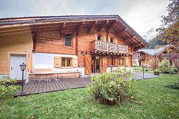 A large wooden house with a balcony and a lawn in front of it