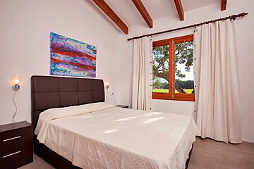 A bedroom with a painting on the wall above the bed