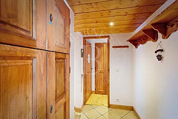 Rustic hallway featuring extensive wooden elements: large built-in closets, doors, planked ceiling, decorative shelf, and tiled floor.