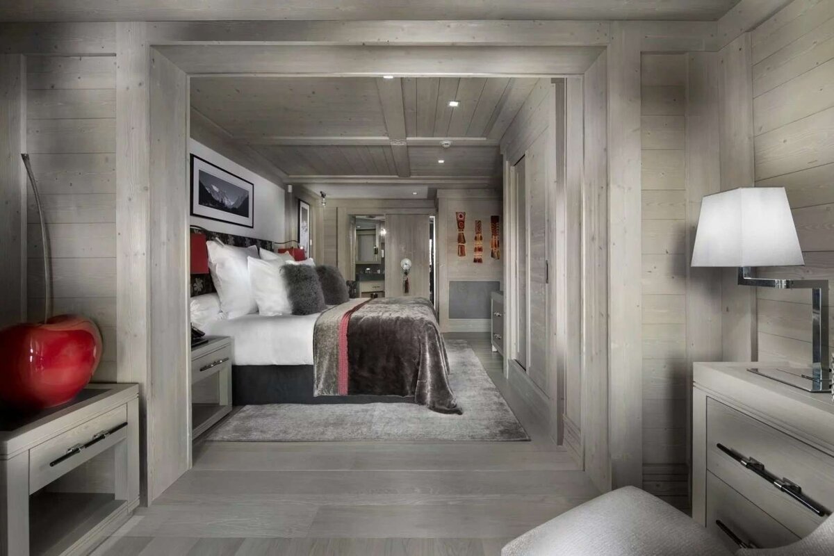 A chic, wood-paneled bedroom in neutral tones, featuring a large bed, elegant furnishings, and a cozy, modern chalet-style design.