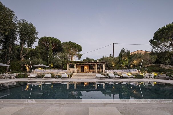 A large swimming pool surrounded by chairs and umbrellas