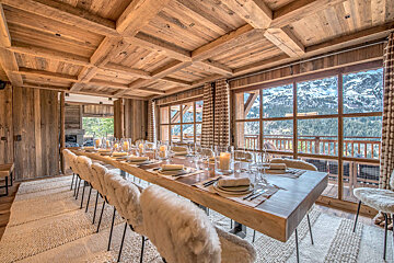 A dining room with a long wooden table and chairs