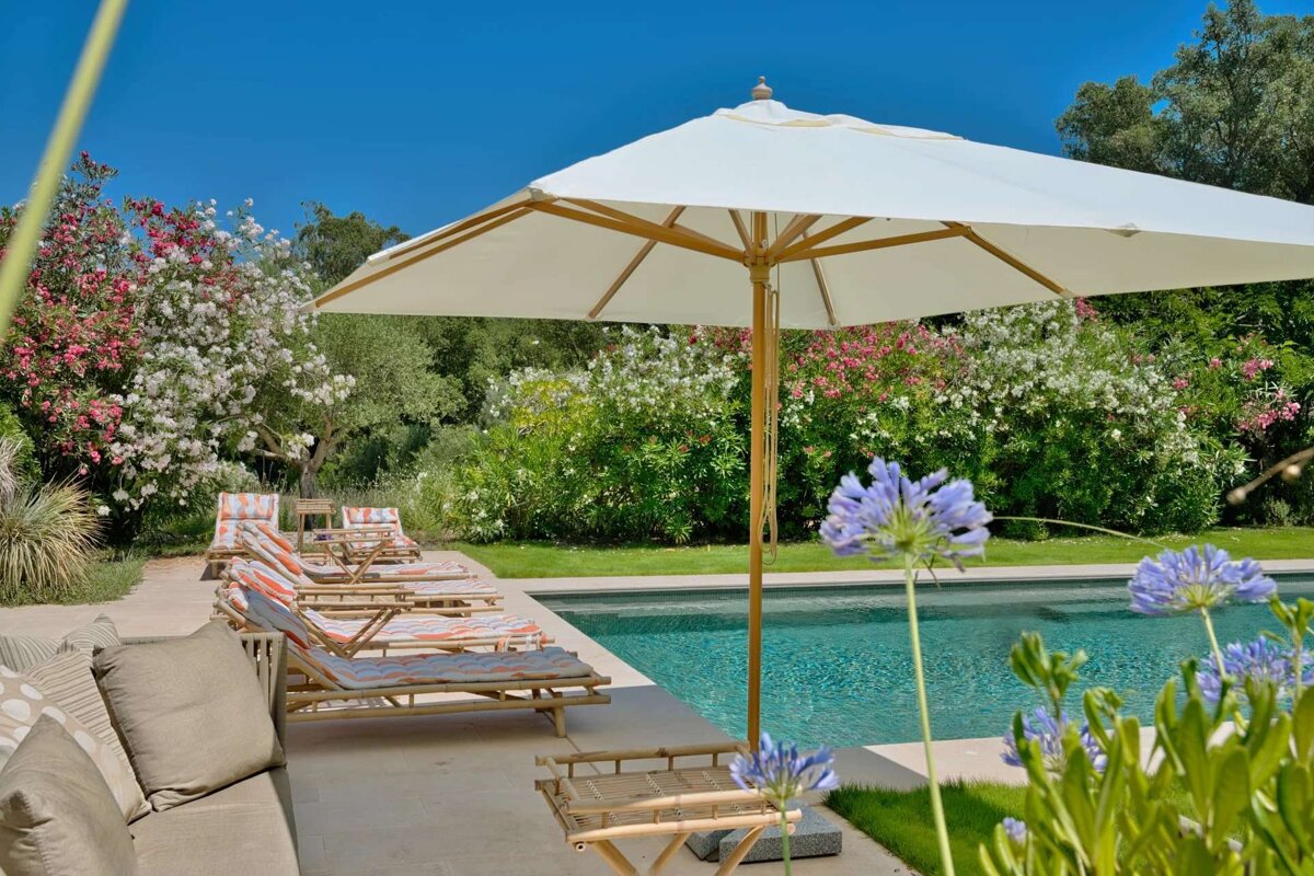 A white umbrella sits in front of a swimming pool