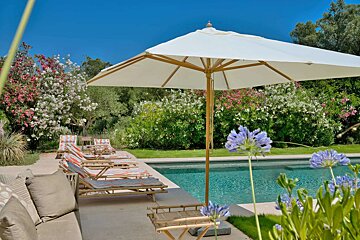 A white umbrella sits in front of a swimming pool