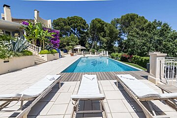 A large swimming pool is surrounded by lounge chairs