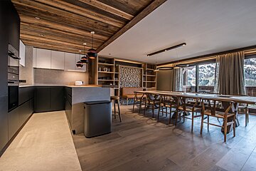A kitchen with a table and chairs and a trash can