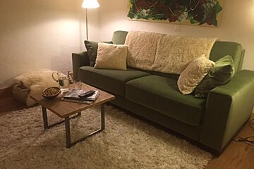 A living room with a green couch and white pillows