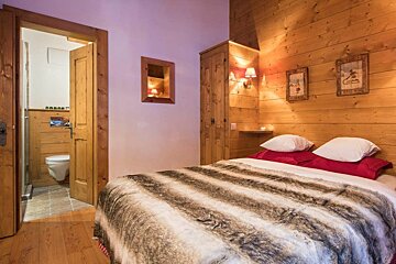 A bedroom with wood paneling and a bed with a fur blanket