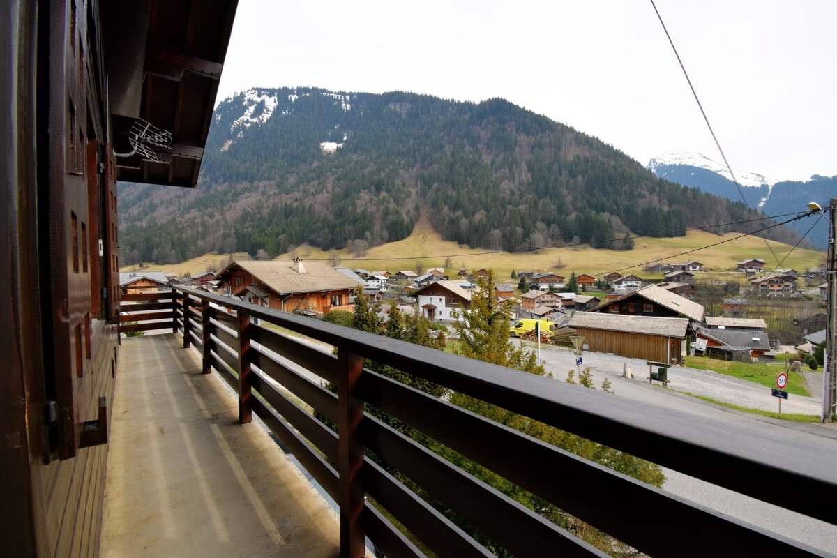 A balcony overlooking a small village with mountains in the background