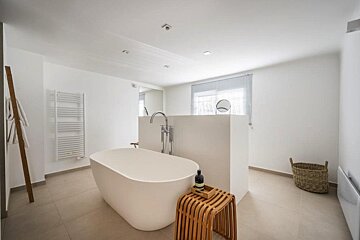 A bathroom with a bathtub and a basket on the floor