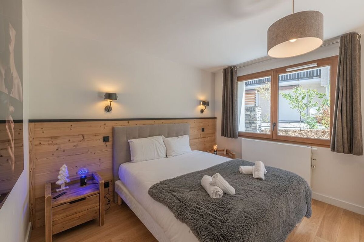 A bedroom with a bed and a nightstand with a clock that says 10:08