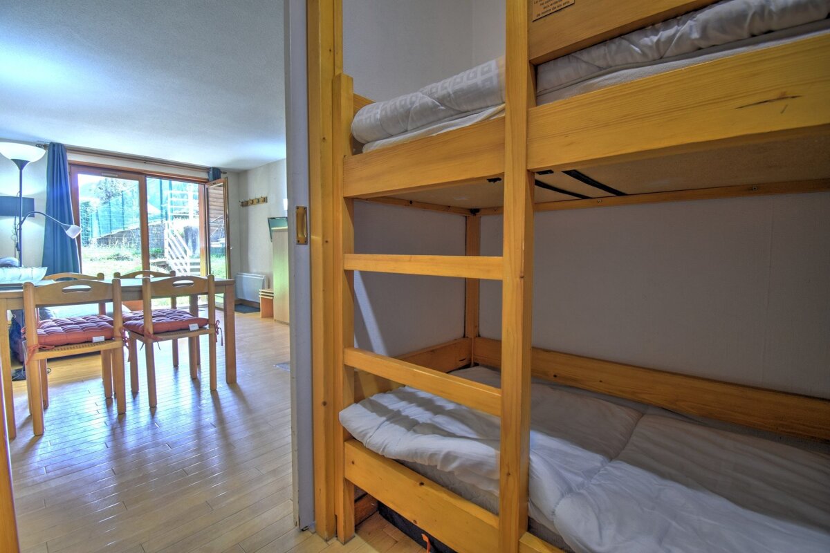 Bunk beds flank a doorway opening to a dining area with wood floors and sliding glass doors leading to an outdoor space.