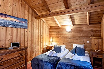 A bedroom with two beds and a painting on the wall