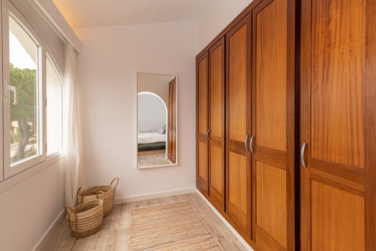 A walk in closet with wooden cabinets and a mirror