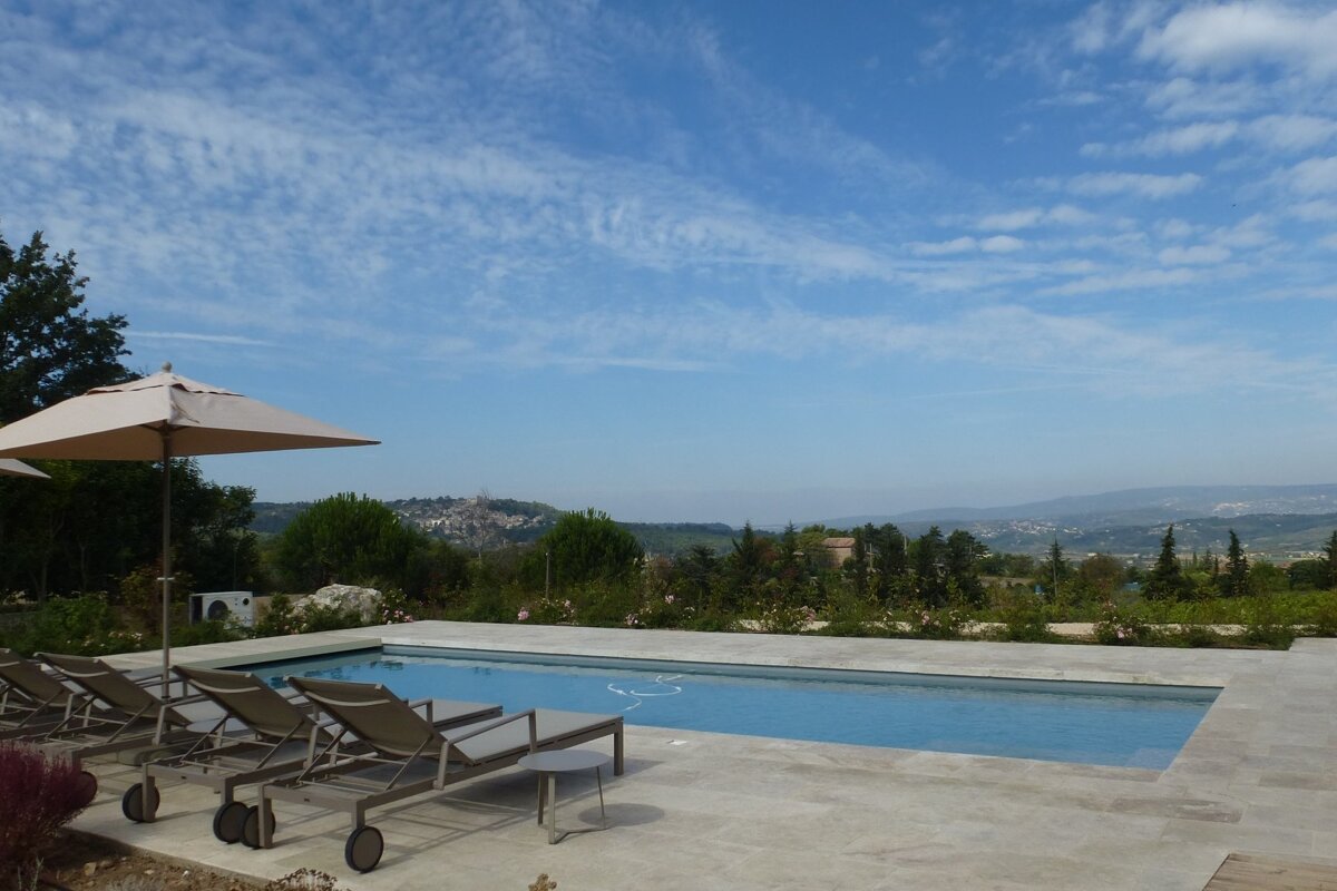 A large swimming pool surrounded by chairs and umbrellas