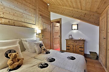 A bedroom with a teddy bear on the bed