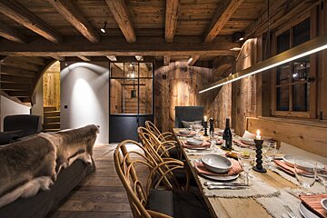 A dining room with a long wooden table and chairs