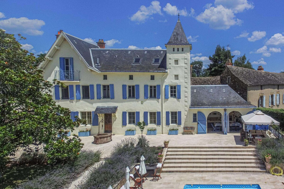 A large white house with blue shutters and a tower