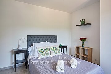 A bedroom with a bed made in provence by janssens immobilier