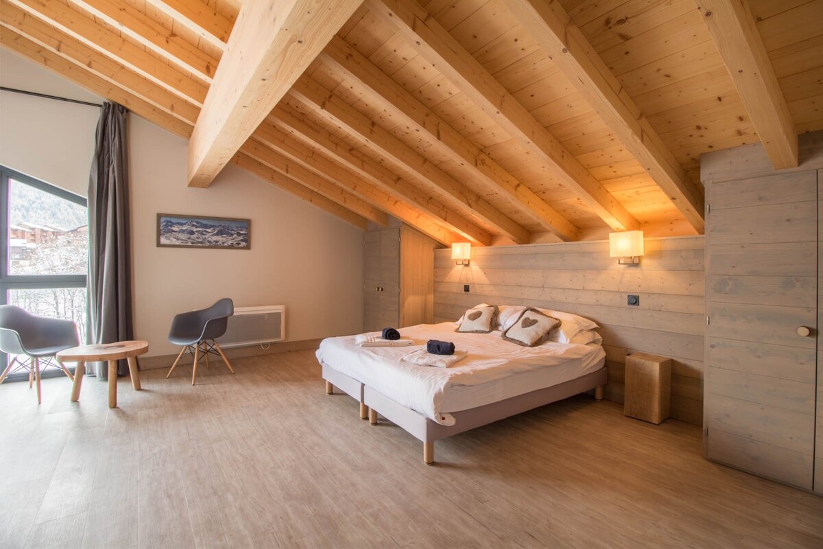 A bedroom with a wooden ceiling and a bed