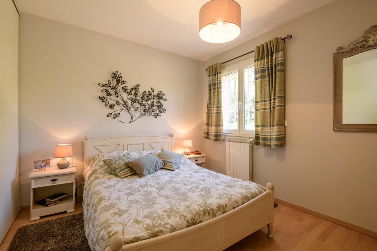 A bedroom with a bed a nightstand and a mirror