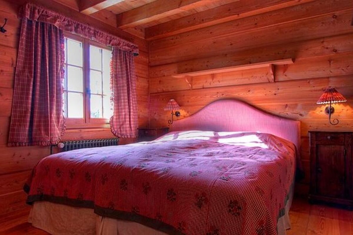 A bedroom in a log cabin with a bed and two lamps