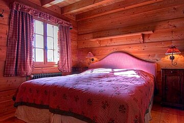 A bedroom in a log cabin with a bed and two lamps