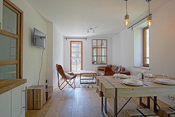 A living room with a table and chairs and a flat screen tv