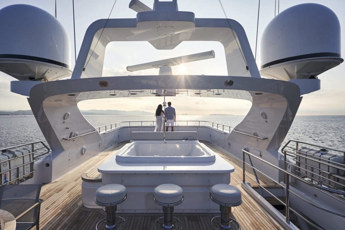 A man and woman are standing on the deck of a yacht