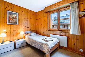 A bedroom with wood paneling and a single bed