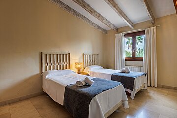 A bedroom with two twin beds and a window