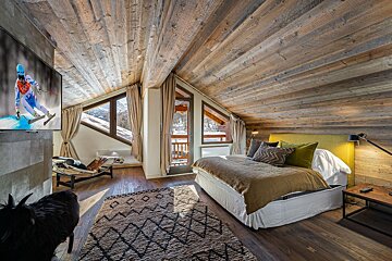 A bedroom with a large bed and a television showing a skier