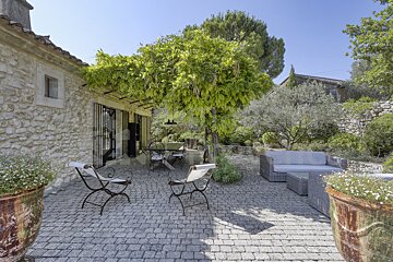 A patio with a couch and chairs under a tree