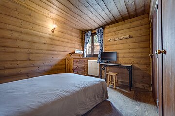 A bedroom with a bed and a desk with a computer on it