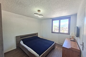 A small bedroom with a bed and a window