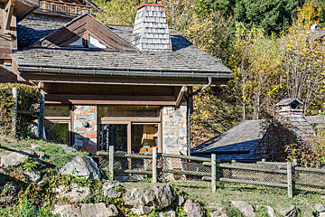 A small stone house with a wooden fence around it