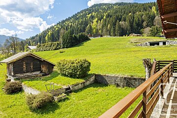 A balcony with a view of a lush green field and mountains