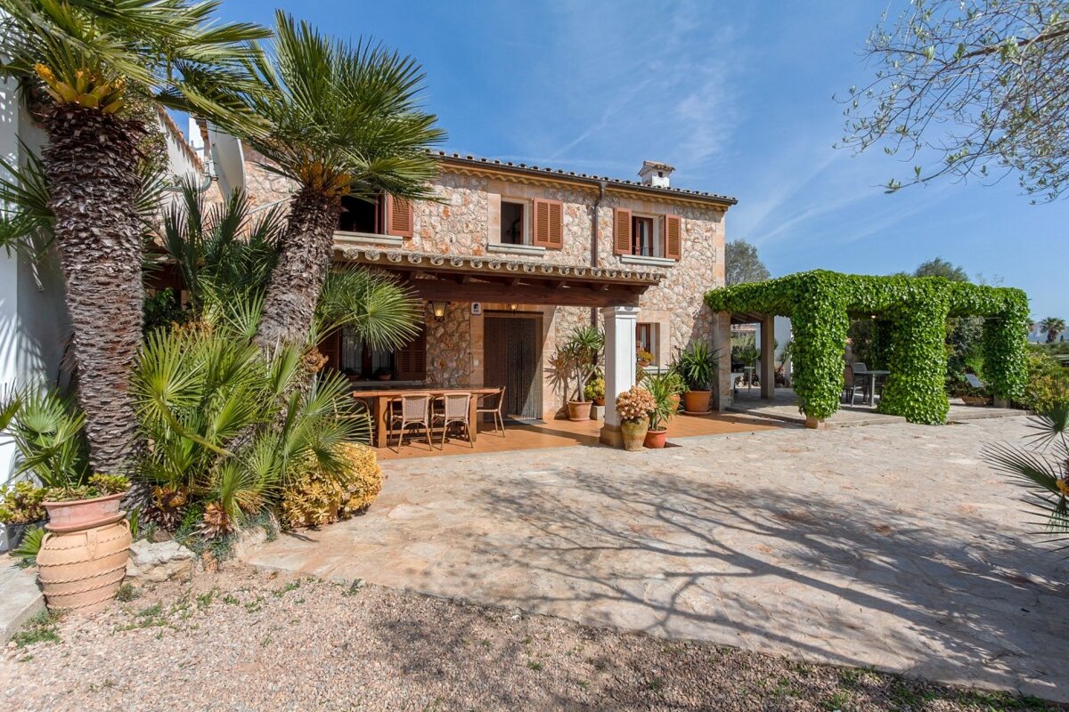 A stone house with a porch and a table and chairs