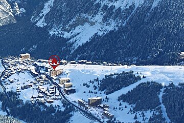An aerial view of a ski resort with a red circle pointing to a building
