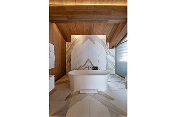A bathtub in a bathroom with a wooden ceiling