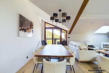 A dining room with a table and chairs and a white management logo on the wall